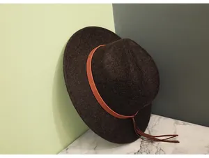 Nahaufnahme brauner Wollfilzhut mit orangefarbenem Lederband und Fransen-Applikation