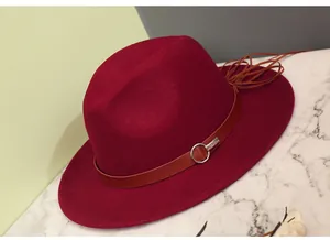 Detail of wine red wool fedora hat featuring a brown leather band and silver ring accent