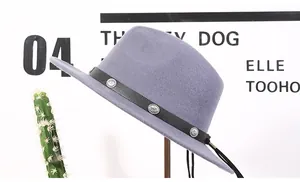 Detail of greyish-purple wool fedora hat featuring a studded black leather band and tassel