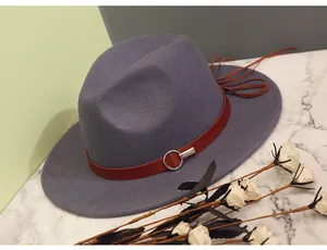 Detail of wool fedora hat with brown leather band and metal buckle on marble surface