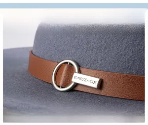 Macro detail of grey wool fedora featuring brown leather band and silver metal buckle