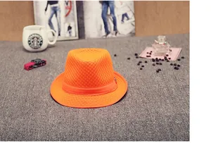 Macro detail of breathable bright orange mesh fedora with metal logo and ribbon band