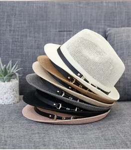 Close-up of stacked straw fedora hats with leather bands and gold buckles