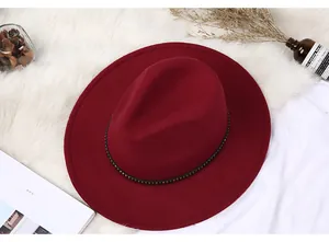 Macro shot of burgundy wool fedora hat with elegant black strap and gold buckle detail