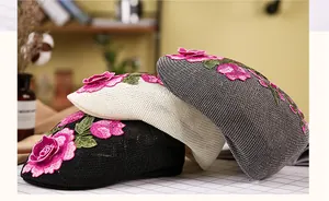 Detail der rosa Rosenstickerei auf Strick-Barett-Mützen in Schwarz, Beige und Grau