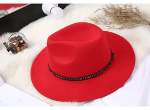 Detail of red fedora hat featuring a black belt with vintage square metal studs