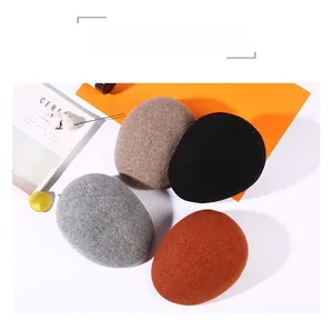 Detailed overhead view of wool beret hats in grey, camel, black, and caramel colors