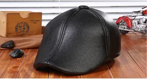 Detail of black faux leather newsboy cap with textured finish on vintage wooden background
