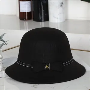 Eleganter schwarzer Wollfilz-Fischerhut mit Schleife und goldenem Stern auf weißem Marmor