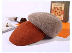 Detail of wool blend flat caps in orange and tan with warm autumn texture