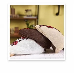 Detail of embroidered floral patterns on knitted mesh berets in white and beige