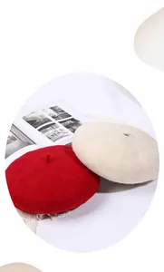 Detail von Wollfilz-Baskenmützen in Rot und Beige auf einem Magazin-Hintergrund