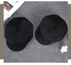 Detail view of two black wool blend newsboy caps with classic eight-panel crown design