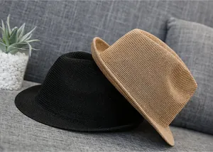 Detail of woven straw fedora hats in black and khaki colors on a soft gray sofa