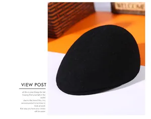Detailed view of a thick black wool beret cap set against warm autumn props and decor