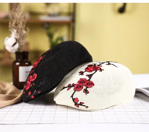 Details von Vintage-Baskenmützen in Schwarz und Beige mit roter Blumenstickerei
