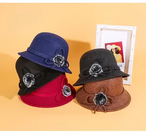 Détail de cinq chapeaux dôme en feutre de laine de couleurs variées avec nœud et pompon