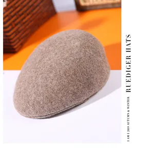 Close-up of light brown wool flat cap on a pedestal showing thick warm winter texture