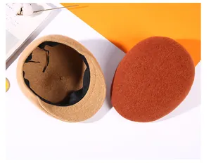 Detailed view of camel and brick red wool newsboy caps showing soft felt texture and inner band