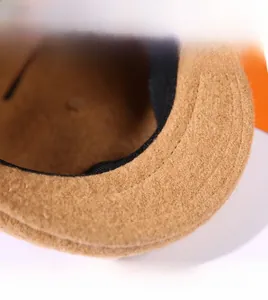Macro detail of the wide-brimmed camel wool flat cap featuring reinforced double stitching