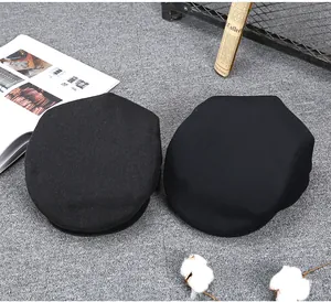 Flat lay of two black vintage newsboy caps on grey carpet with retro magazine decor