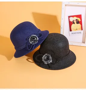 Détail de chapeaux cloches en laine avec pompons en fourrure et nœuds en bleu et gris