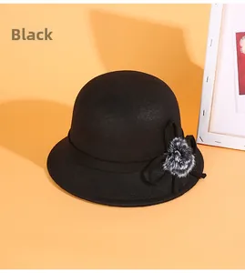 Détail d'un chapeau cloche en feutre noir avec un nœud élégant et un pompon gris doux