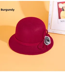 Gros plan d'un chapeau en laine bordeaux avec un nœud latéral et un petit pompon chic