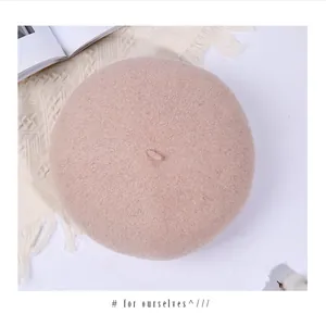 Draufsicht auf rosa Wollbaskenmütze mit Stiel-Detail auf strukturiertem Stoff