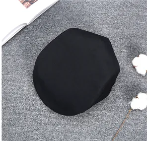 Flat lay of a black vintage wool newsboy hat on grey texture with cotton branch