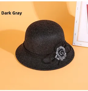 Détail d'un chapeau cloche en feutre de laine gris foncé avec nœud floral et pompon en fourrure