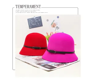 Detail view of red and rose wool felt cloche hats with black leather belts and buckles
