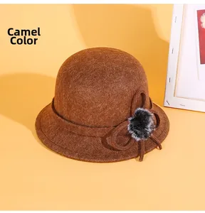 Détail d'un chapeau cloche en feutre camel avec nœud élégant et pompon décoratif