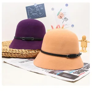 Detail of wool cloche hats in purple and tan with black leather bands and metal buckles