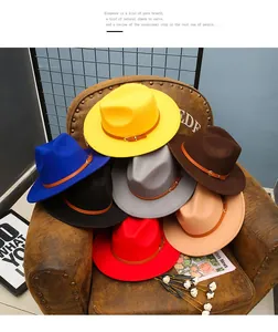Stack of multi-color felt fedora hats with leather belts on a vintage leather armchair