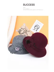 Dettaglio di cappelli cloche in lana grigio e bordeaux con fiori decorativi e accenti di perline