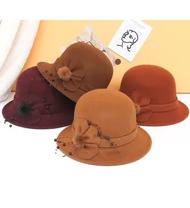 Dettaglio di cappelli cloche in lana con fiori in tessuto e pompon in morbida pelliccia
