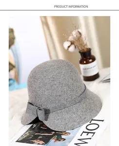 Detail view of deep grey wool felt cloche hat with a bow on soft white plush background