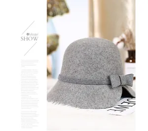 Detail of grey wool cloche hat with a bow and side notch on a cozy white plush background