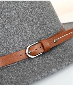Detailed close-up of grey felt fedora featuring brown leather band with silver buckle