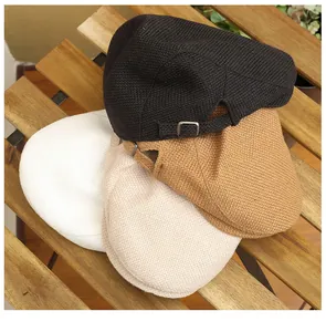 Close-up of woven ivy caps in black, khaki, and white showing side metal buckle details