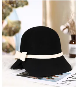 Detail of elegant black wool dome hat with cream bow on luxury faux fur background