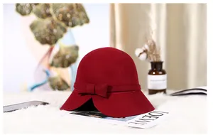 Detail of dark red wool felt cloche hat featuring a bow and asymmetric brim design