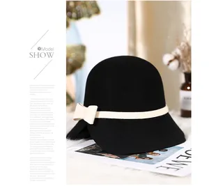 Detailed view of a black wool cloche hat with a contrast cream bow and decorative band