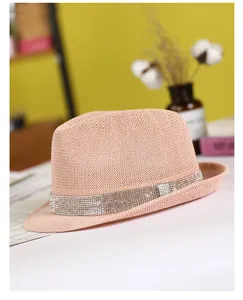Detail of pink straw fedora hat with elegant rhinestone band and woven texture closeup