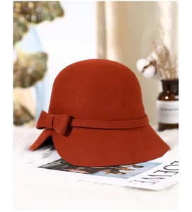 Detail of wool cloche hat with stylish brim notch and ribbon bow on plush background
