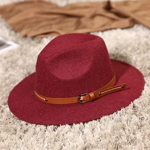 Classic burgundy fedora hat with brown leather belt detail on stylish textured background
