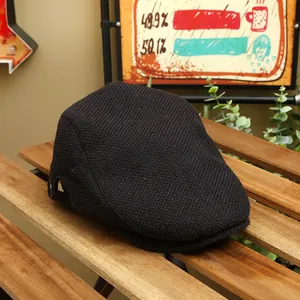 Classic black knitted flat cap with woven texture on a rustic wooden table background