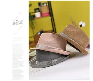 Straw fedora hats in pink grey and brown with shiny rhinestone bands on a table