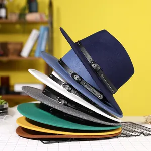 Classic colorful felt fedora hats stacked with leather belts on a warm yellow background